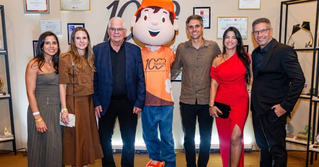 Executivos e convidados posam ao lado do mascote durante evento dos 100 anos do Grupo São Luiz