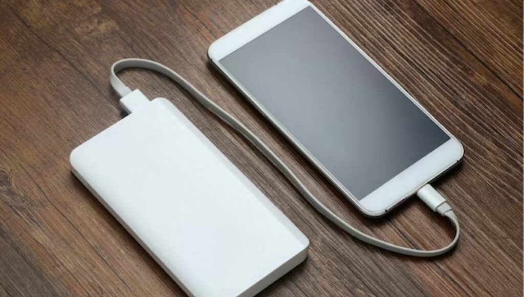 Power bank conectado a celular ilustrando regras de uso em avião e restrições da Anac