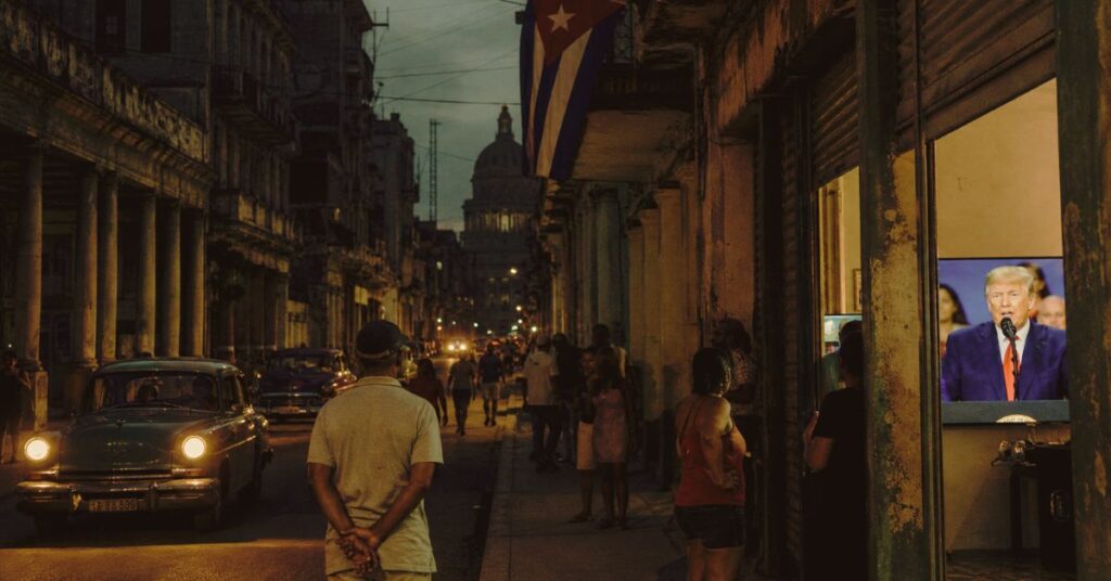 Rua de Havana durante apagão com bandeira cubana e TV exibindo Donald Trump, em meio à pressão dos EUA sobre Cuba