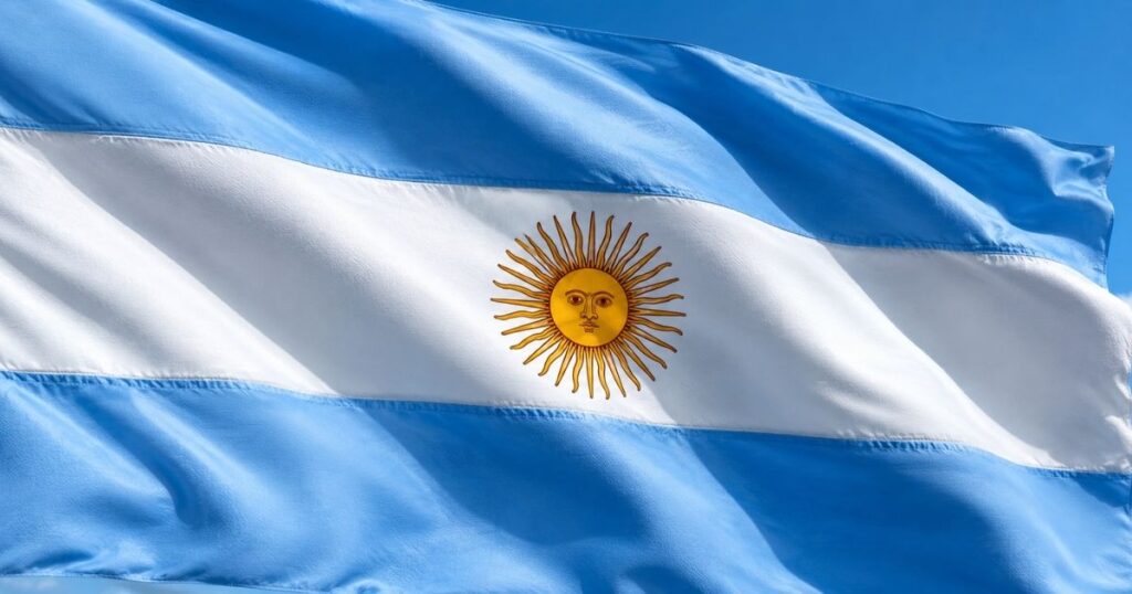 Bandeira da Argentina tremulando ao vento em imagem que ilustra a retomada dos investimentos no país e os desafios relacionados ao risco político.