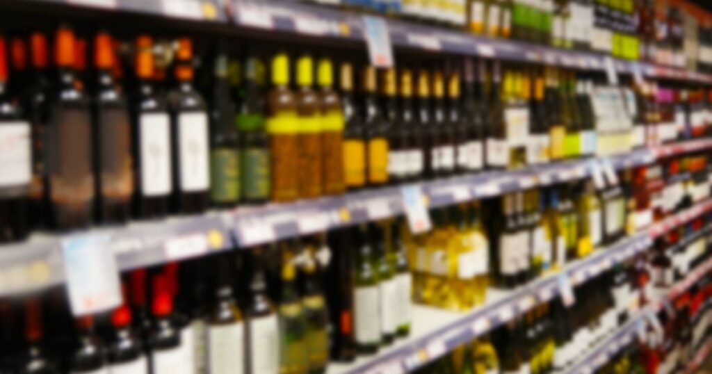 Prateleira de supermercado com garrafas de bebidas alcoólicas expostas em seção de vinhos durante debate sobre o imposto do pecado previsto para 2027.
