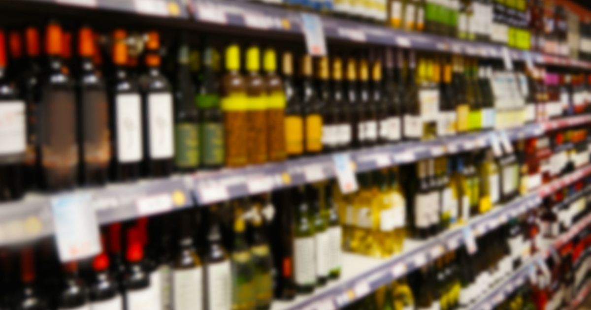 Prateleira de supermercado com garrafas de bebidas alcoólicas expostas em seção de vinhos durante debate sobre o imposto do pecado previsto para 2027.
