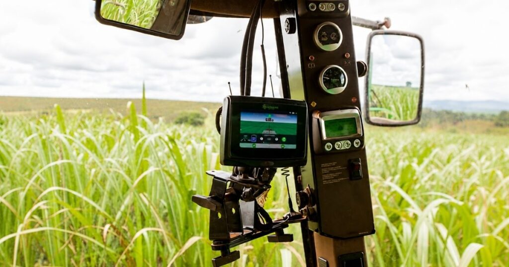 Monitor de navegação por satélite instalado em máquina agrícola durante operação em lavoura; estudo investiga interferência em sinais de GPS e GNSS.