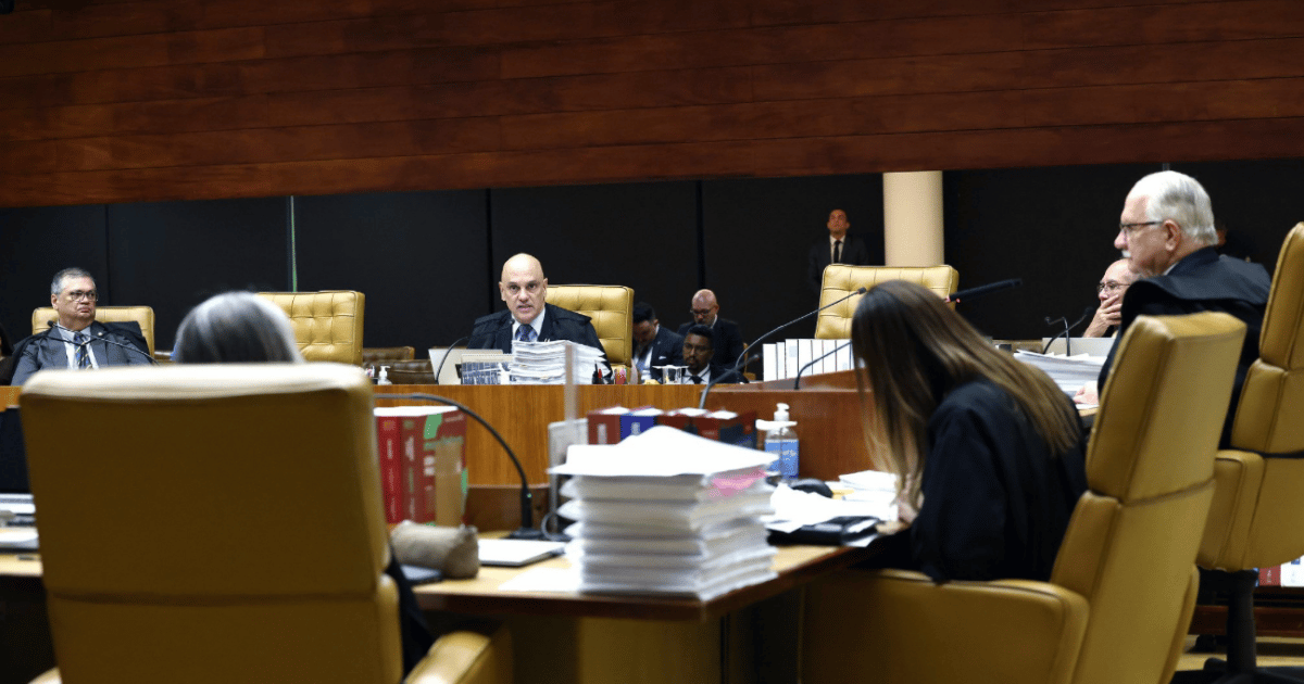 Magistrados reunidos em plenário de tribunal superior durante sessão de julgamento, com processos e documentos sobre a mesa.