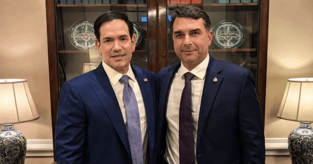 Marco Rubio e Flávio Bolsonaro posam juntos durante encontro oficial nos Estados Unidos em meio à troca de cartas sobre equipe de transição e relações comerciais.