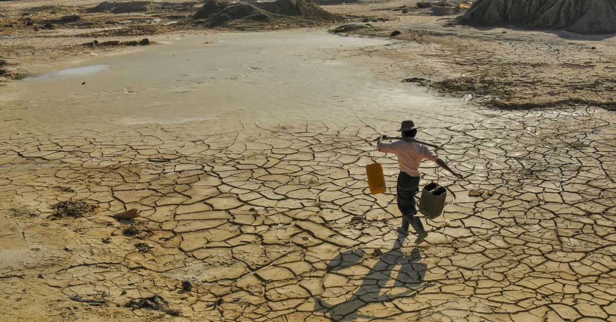 Homem caminha sobre solo rachado em área seca, imagem que ilustra os impactos das mudanças climáticas no Brasil