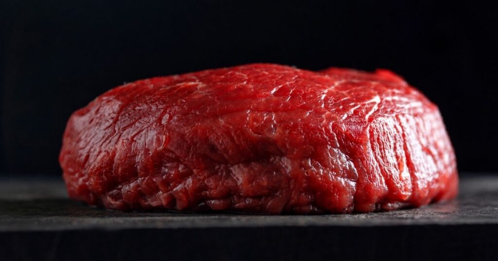 Peça de carne bovina crua em destaque após decisão da União Europeia que restringe exportações brasileiras por exigências sobre controle de antimicrobianos.