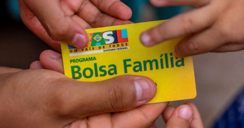 Cartão do Bolsa Família sendo segurado por mãos durante atendimento relacionado à atualização do Cadastro Único.