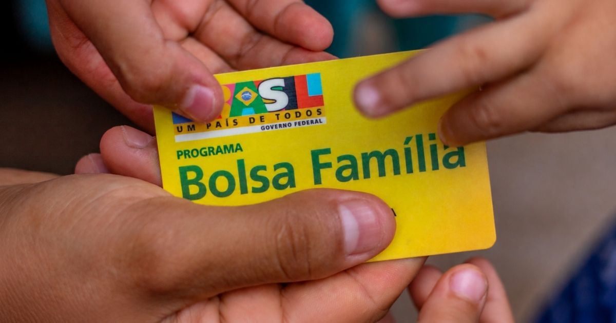 Cartão do Bolsa Família sendo segurado por mãos durante atendimento relacionado à atualização do Cadastro Único.