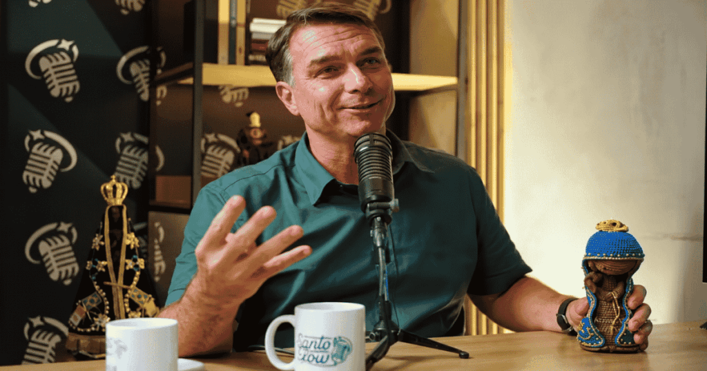 Flávio Bolsonaro segura imagem de Nossa Senhora Aparecida durante participação em podcast