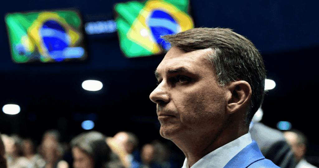 Flávio Bolsonaro durante evento com bandeiras do Brasil ao fundo