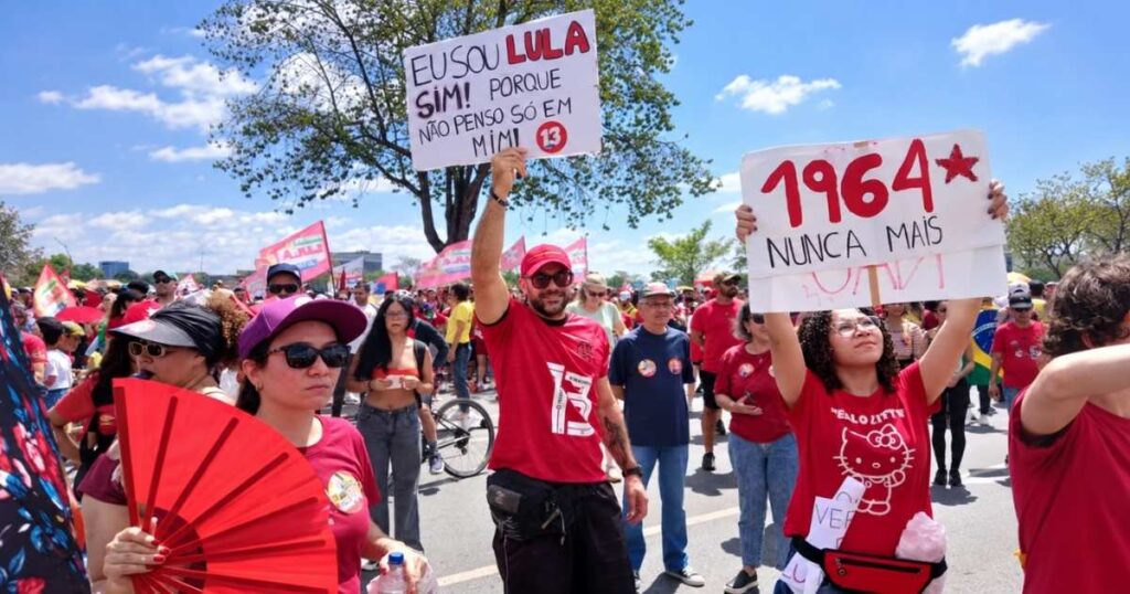 Apoiadores de Lula participam de manifestação em Brasília, segurando cartazes em defesa do presidente e contra a ditadura militar.