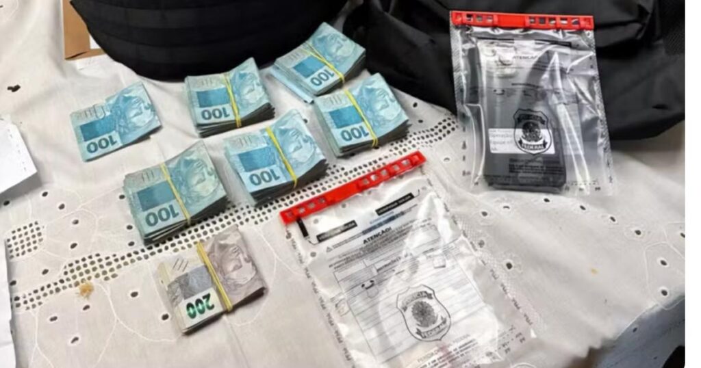 Maços de dinheiro em reais, celular e materiais recolhidos pela Polícia Federal durante a Operação Em Nome do Pai.