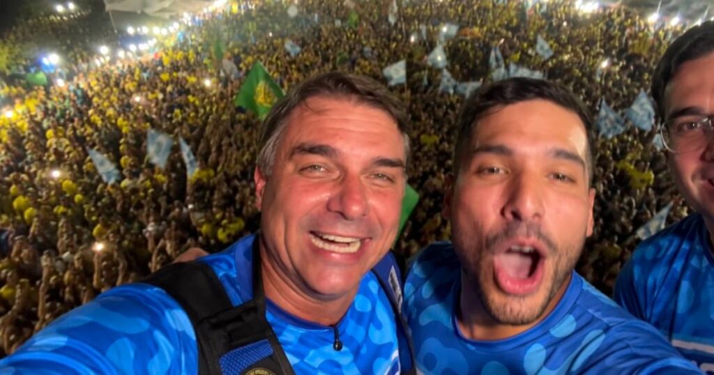 Flávio Bolsonaro e André Fernandes aparecem em primeiro plano durante ato de campanha com multidão de apoiadores em Fortaleza, no Ceará.