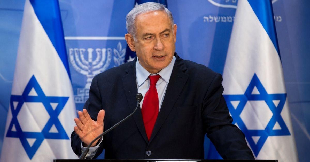 Benjamin Netanyahu discursa diante de bandeiras israelenses em imagem ilustrativa sobre a eleição em Israel e as tensões com o Irã.