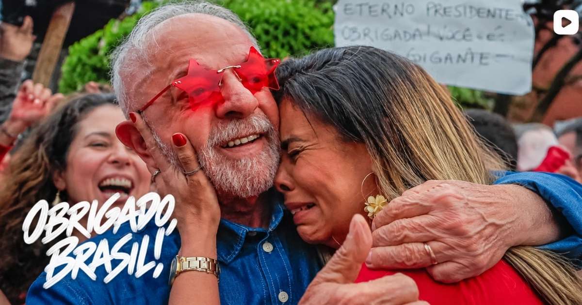 Luiz Inácio Lula da Silva, usando óculos vermelhos em formato de estrela, abraça uma mulher emocionada durante comemoração de sua reeleição presidencial em 2026.